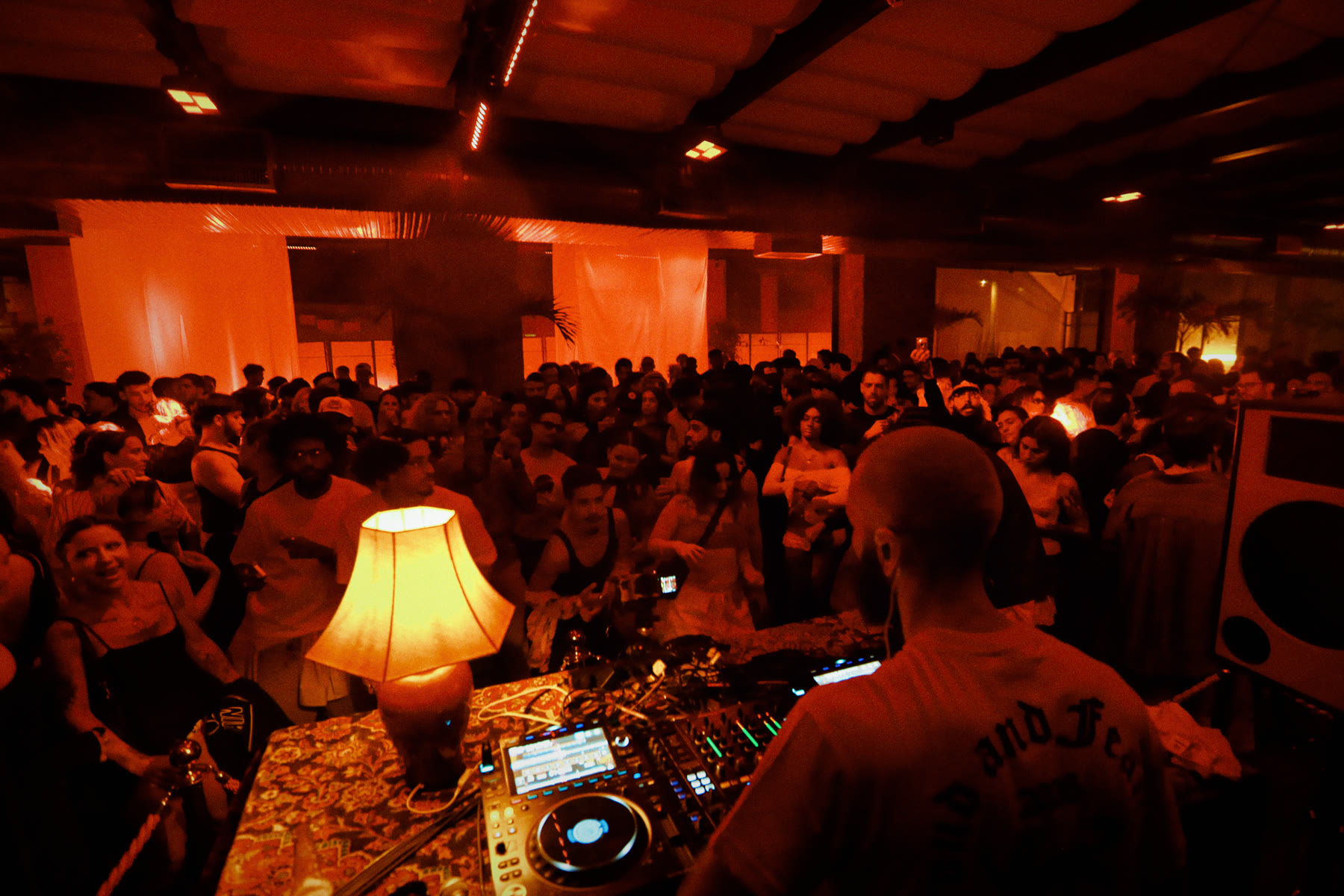 DJ na cabine, com a pista lotada atrás