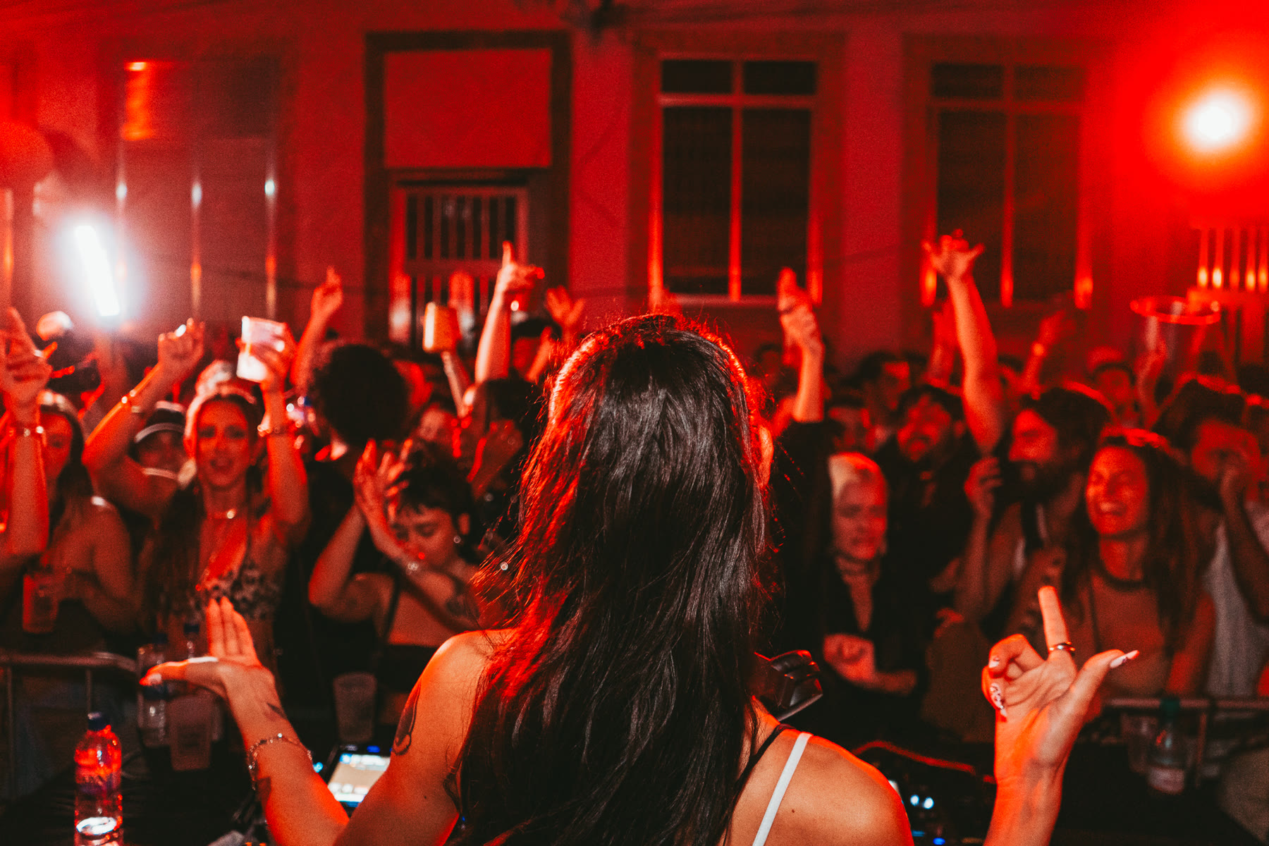 DJ de costas para a pista, mãos para o alto